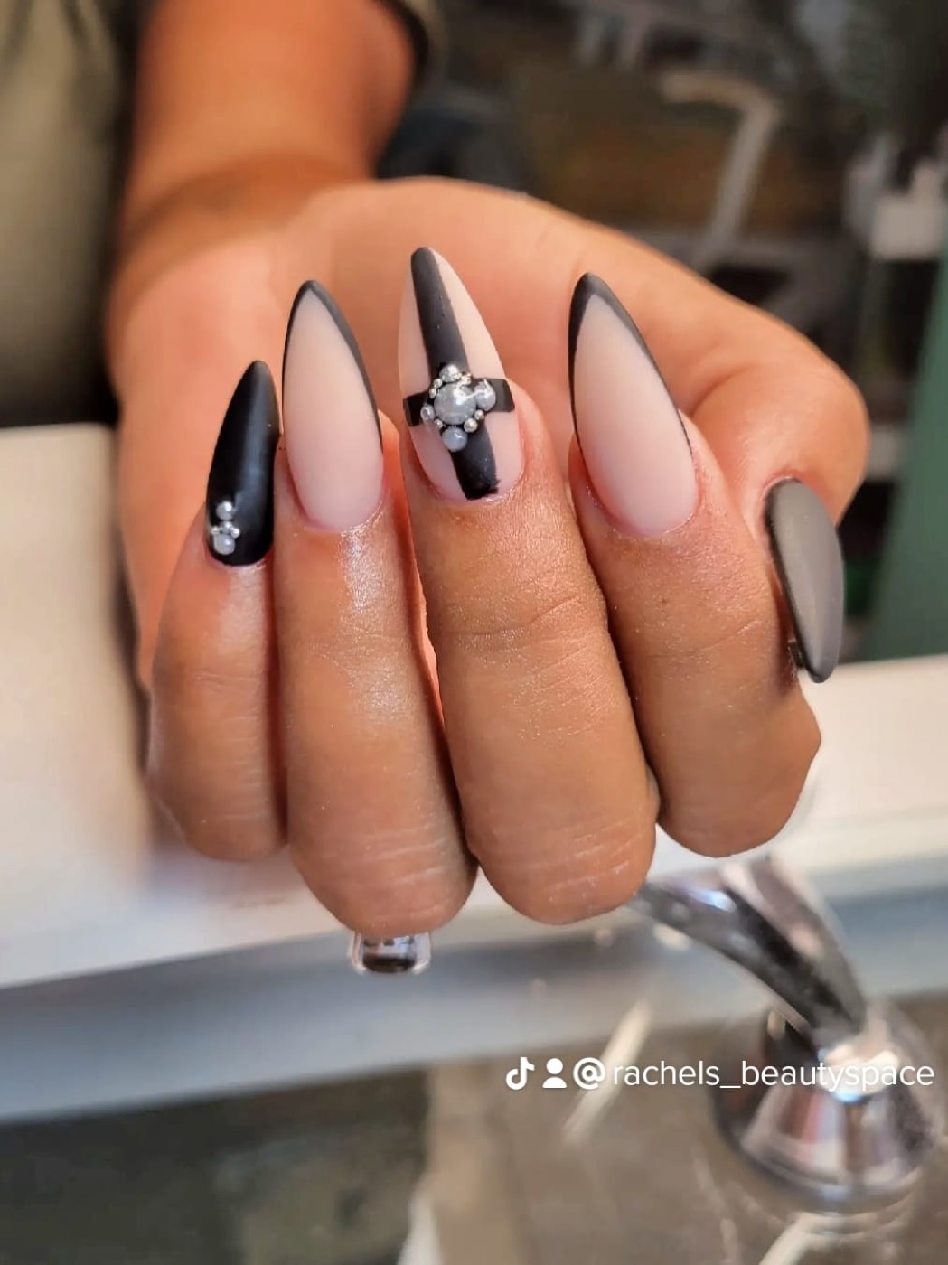 Matte black and nude almond nails with a rhinestone cluster accent nail