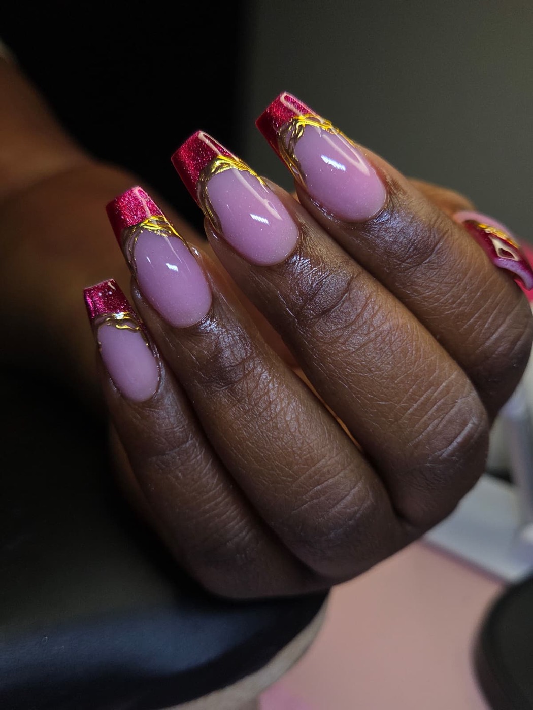 Coffin nails with red glitter French tips outlined in gold chrome